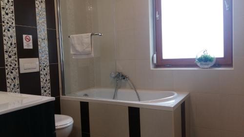 y baño con bañera, aseo y lavamanos. en Váralja Apartman en Tata