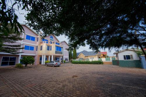 a car parked in a parking lot in front of a house at Pemicsa Hotel Accra in Spintex