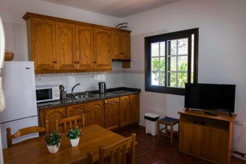 cocina con armarios de madera y mesa con TV en Casa del Cu bano B- Biosphere Reserve, en Santa Cruz de Tenerife