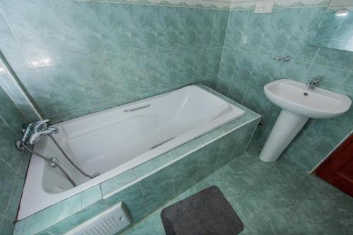 a bathroom with a bath tub and a sink at Pemicsa Hotel Accra in Spintex