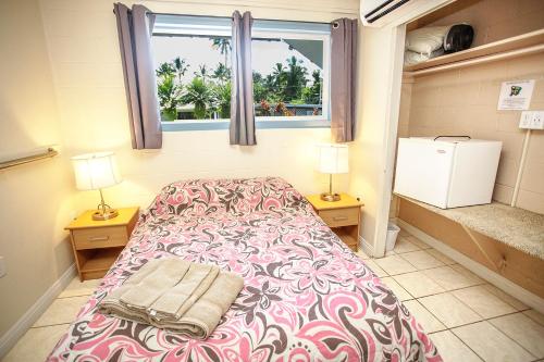 a bedroom with a bed and two lamps and a window at Arnott's Lodge & Hiking Adventures in Hilo