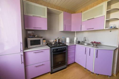 a kitchen with purple cabinets and a microwave at PaulMarie Apartments on Molodeznaya in Soligorsk