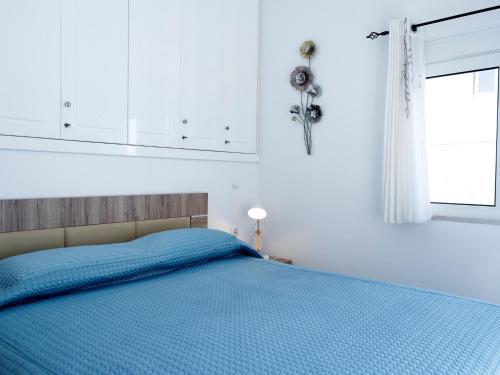 a bedroom with a blue bed with a window at Haraki Beach Mediterranean Retreat in Haraki