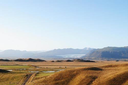 a view of a field with mountains in the background at Miðsker 1 in Höfn