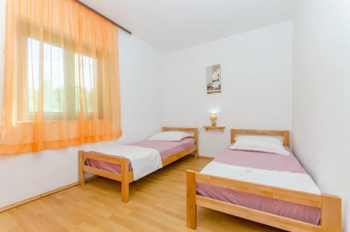 two beds in a room with a window at Apartment Vitaic in Supetar
