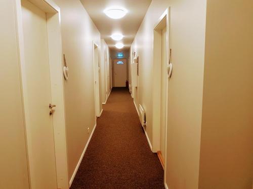 a hallway with white walls and a long hallway with doors at Skálatjörn Guesthouse in Skálatjörn