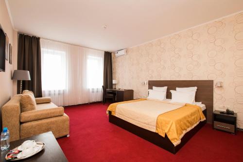 um quarto de hotel com uma cama e uma cadeira em Premier Hotel em Níjni Novgorod