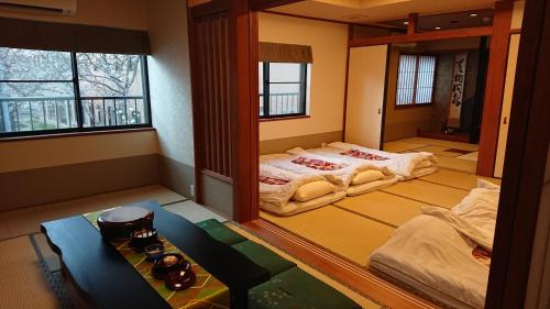 Zimmer mit 2 Betten und einem Tisch in der Unterkunft Show和の宿つちや～豊臣の隠れ茶の間～ in Nagoya