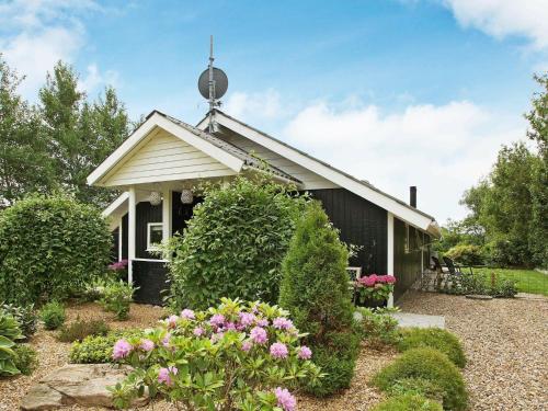 a small black house with flowers in front of it at 8 person holiday home in Tarm in Hemmet