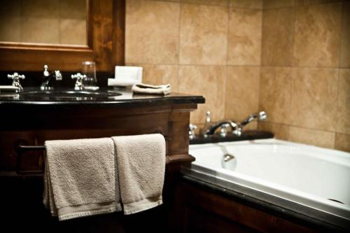 a bathroom with a tub and a sink with towels at Hôtel Les Barmes De l'Ours in Val-d'Isère