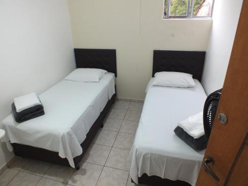 2 camas en una habitación pequeña con sábanas blancas en Hospedagem Henri Dunant, en São Paulo