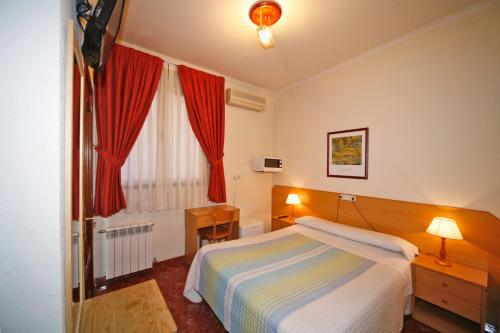 1 dormitorio con 1 cama y una ventana con cortinas rojas en Hostal Prim, en Madrid