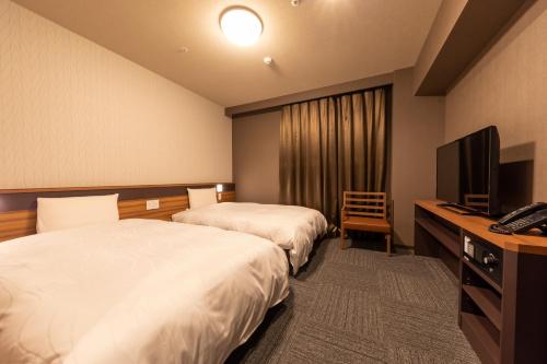 a hotel room with two beds and a television at Dormy Inn Kawasaki Natural Hot Spring in Kawasaki