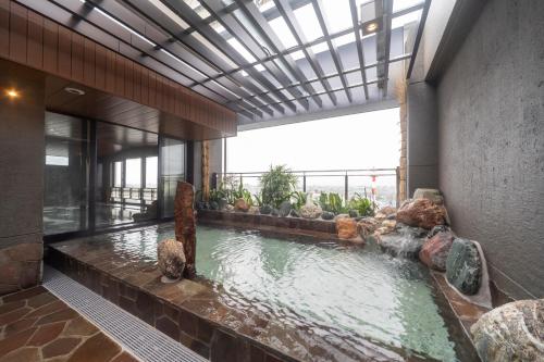 a swimming pool in a building with a large window at Dormy Inn Kawasaki Natural Hot Spring in Kawasaki