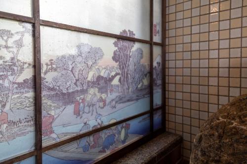 a window in a bathroom with a painting on the wall at Dormy Inn Kawasaki Natural Hot Spring in Kawasaki