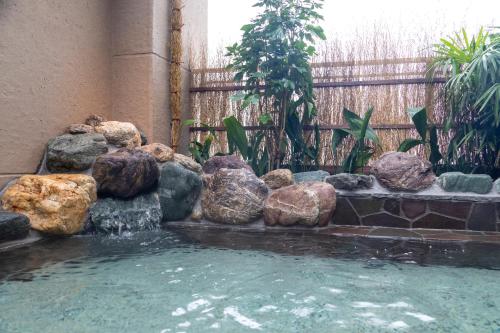 a pool of water with rocks in a garden at Dormy Inn Kawasaki Natural Hot Spring in Kawasaki