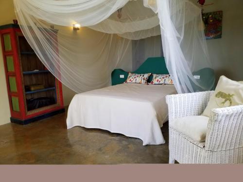 a bedroom with a bed with a canopy and a chair at Villa Los Gorgones in Las Galeras