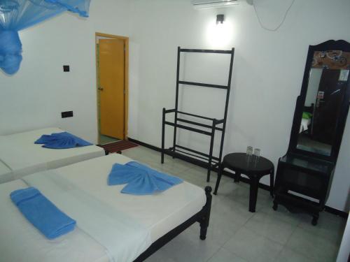two beds in a room with a chair and a table at Green Garden Guest Mirissa in Mirissa