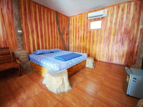 een slaapkamer met een bed en een houten vloer bij U Thong Hotel in U Thong