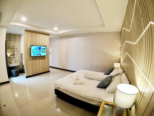 a bedroom with a bed and a tv on a wall at The Vista Pool Villa in Kanchanaburi