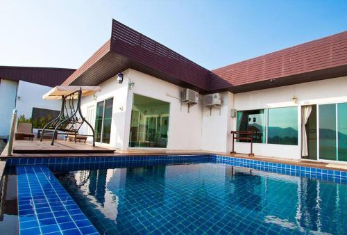 a swimming pool in front of a house at The Vista Pool Villa in Kanchanaburi