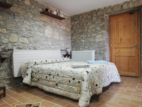 Calvi dellʼ UmbriaにあるGiardino casa Selciataの石の壁の中にベッドが置かれた寝室