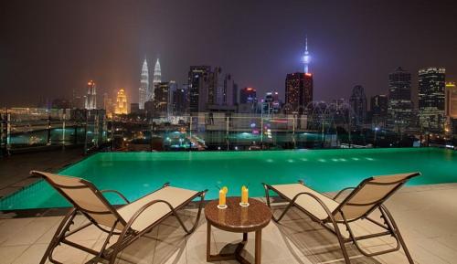 a balcony with chairs and a table with a view of a city at WP Hotel in Kuala Lumpur