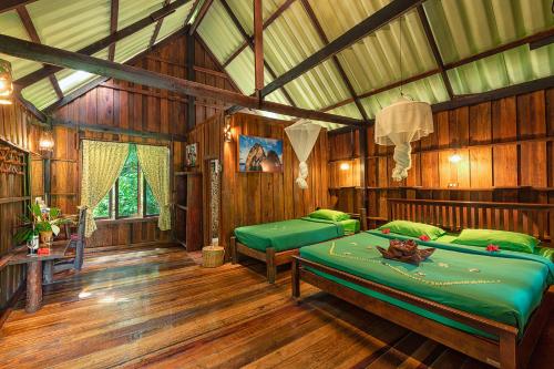 a bedroom with two beds in a room with wooden floors at Khao Sok Riverside Cottages in Khao Sok National Park