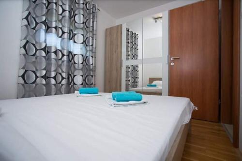 Una cama blanca con dos almohadas azules encima. en Apartman Mila, en Kaštela
