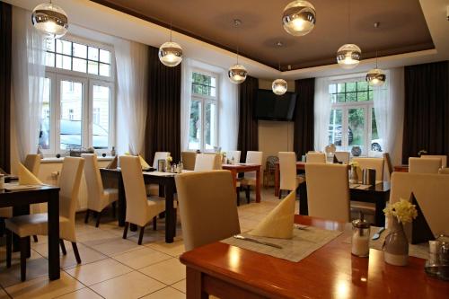 una sala da pranzo con tavoli, sedie e finestre di Hotel La Passionaria a Mariánské Lázně