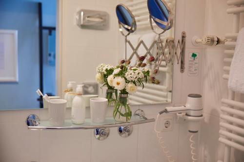 a bathroom with a vase of flowers on a shelf at Hotel Metropol by Maier Privathotels in Munich