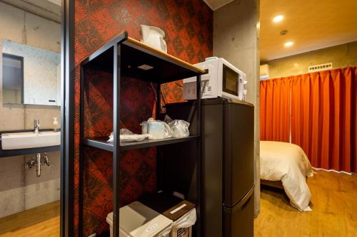 Habitación con nevera y dormitorio con cama. en Hotel Little Island Okinawa Matsuyama en Naha