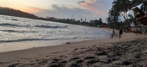 a couple of people walking on the beach at Bisandu guesthouse in Mirissa