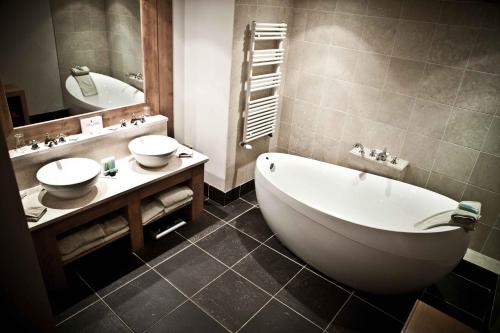 a bathroom with a tub and a sink and a mirror at Hôtel Les Barmes De l'Ours in Val dʼIsère
