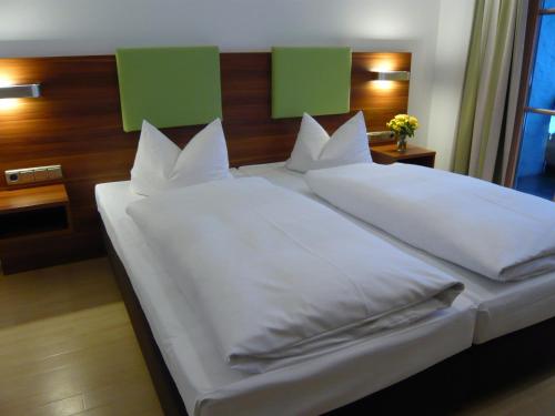 a large white bed with white sheets and pillows at Hotel Das Essigmanngut in Anif