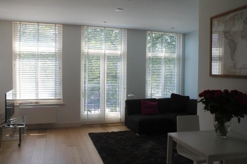 sala de estar con sofá y algunas ventanas en Great Apartment Amsterdam, en Ámsterdam