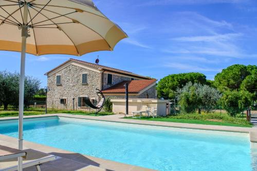 a swimming pool with an umbrella and a house at Poggio Picchio in Bibbona