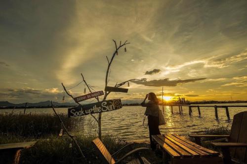 a woman standing next to a sign with the sunset in the background at Hoa Mai Hotel in Dong Hoi