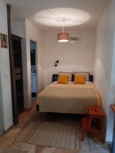 a bedroom with a bed with two orange pillows at Studio Indépendant Millénaire in Montpellier