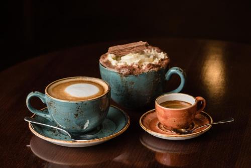zwei Tassen Kaffee und ein Stück Kuchen auf dem Tisch in der Unterkunft Meldrum House Hotel Golf And Country Estate in Oldmeldrum