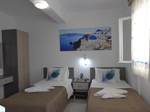 two beds in a room with white walls at Honeymoon Beach Studios in Perivolos