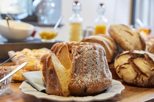 una mesa con un plato de pan y pasteles en Hôtel-SPA Le Moulin De La Wantzenau - Strasbourg Nord, en La Wantzenau