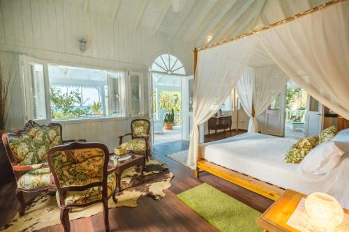 a bedroom with a canopy bed and two chairs at Hotel Casa Coson in Las Terrenas