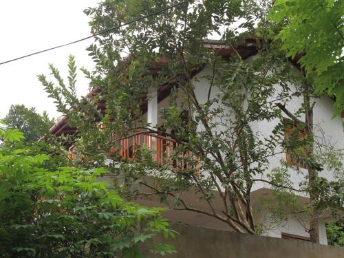 a white building with a balcony and trees at lake paradise in Habaraduwa