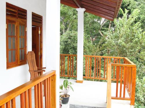 a porch with a wooden railing and a rocking chair at lake paradise in Habaraduwa