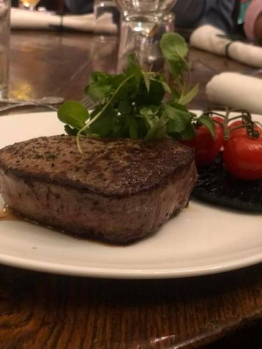 a steak on a white plate with tomatoes and greens at The Swan Hotel, Alresford in Winchester