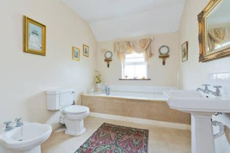 uma casa de banho com 2 lavatórios, uma banheira e um WC. em Buvinda em Drogheda