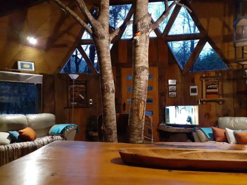 a living room with a large wooden table and trees at Domos Entre Bosques in Malalcahuello