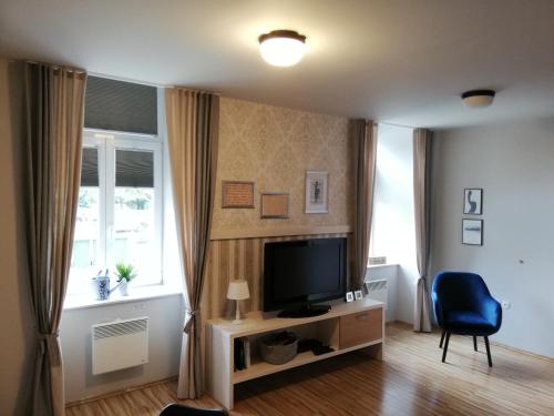 a living room with a television and a blue chair at Apartment Nobl plac in Celje