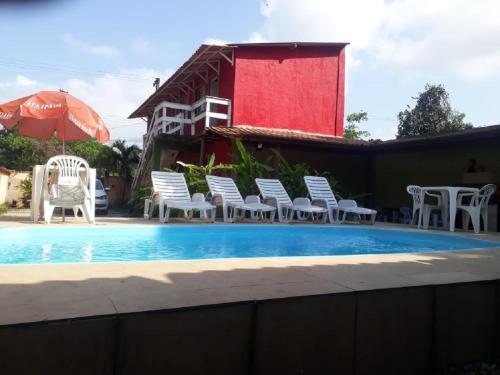 uma piscina com cadeiras brancas e um guarda-sol em Pousada Chalé Boracéia em Boraceia
